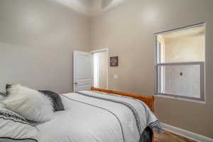 Bedroom featuring a high ceiling and wood-type flooring