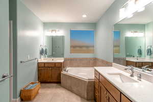 Bathroom with vanity, a relaxing tiled tub, and tile patterned floors