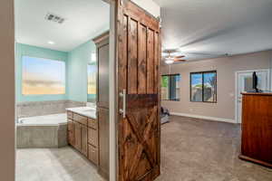 Bathroom featuring vanity, tiled bath, a textured ceiling, and ceiling fan