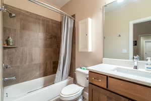 Full bathroom with vanity, shower / bathtub combination with curtain, and toilet