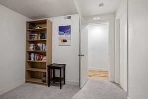 Corridor with light carpet and a textured ceiling