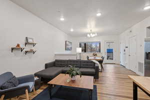 Living room featuring an inviting chandelier, light hardwood / wood-style flooring, and a textured ceiling