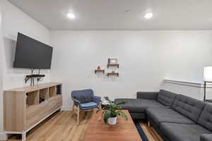 Living room with light hardwood / wood-style floors and a textured ceiling