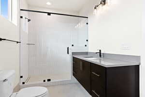 Bathroom with vanity, a shower with shower door, tile patterned floors, and toilet