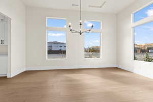 Unfurnished dining area featuring a chandelier and light hardwood / wood-style floors