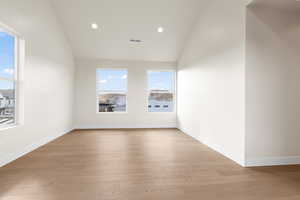 Spare room featuring vaulted ceiling and light hardwood / wood-style floors