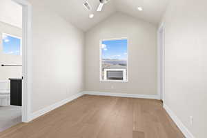 Unfurnished room featuring vaulted ceiling, light hardwood / wood-style floors, and ceiling fan