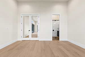 Unfurnished bedroom featuring french doors and light hardwood / wood-style floors