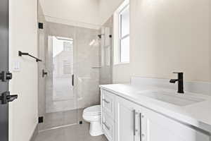 Bathroom featuring vanity, toilet, a shower with shower door, and tile patterned flooring