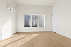 Empty room featuring a wall unit AC and light wood-type flooring