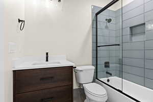 Full bathroom featuring enclosed tub / shower combo, vanity, and toilet