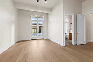 Spare room featuring a high ceiling, ceiling fan, french doors, and light hardwood / wood-style flooring