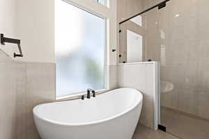 Bathroom featuring tile patterned flooring, shower with separate bathtub, and tile walls