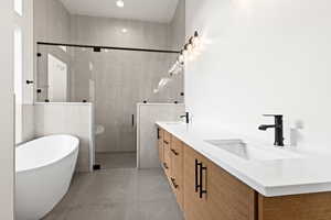 Bathroom featuring tile patterned floors, vanity, and shower with separate bathtub