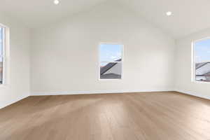 Spare room featuring high vaulted ceiling and light hardwood / wood-style flooring