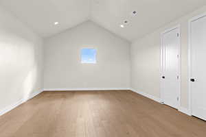 Unfurnished room featuring lofted ceiling and light hardwood / wood-style floors