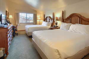 Bedroom with light carpet and vaulted ceiling