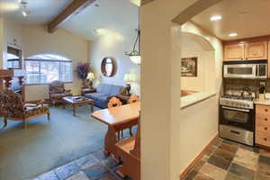 Kitchen featuring pendant lighting, backsplash, stainless steel appliances, lofted ceiling with beams, and light brown cabinetry