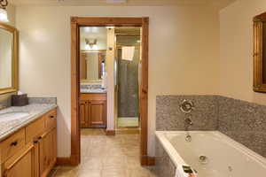 Bathroom with independent shower and bath, vanity, and tile patterned flooring