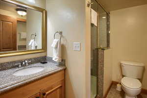 Bathroom with tile patterned flooring, vanity, an enclosed shower, and toilet