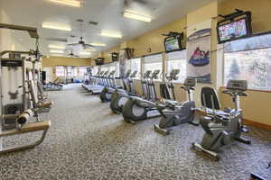 Gym with ceiling fan, a textured ceiling, and carpet