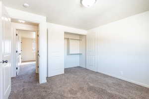 Unfurnished bedroom with a closet, carpet, and baseboards