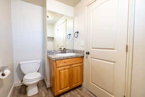 Bathroom featuring vanity, wood finished floors, toilet, and baseboards