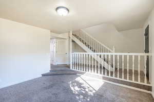 Interior space with stairway, carpet, and baseboards