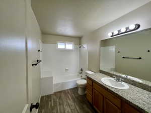 Full bathroom with hardwood / wood-style flooring, vanity, a textured ceiling, toilet, and tiled shower / bath