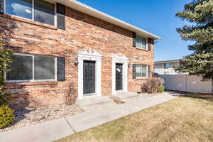 View of front of home with brick siding, a front lawn, and fence