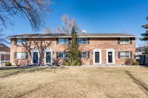 Rear view of property with brick siding, a yard, and fence