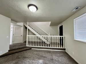 Staircase featuring a textured ceiling and carpet