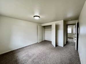 Unfurnished bedroom with carpet floors, a textured ceiling, and a closet