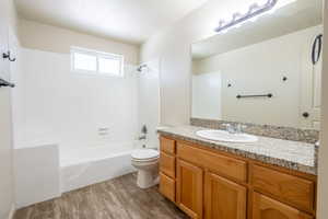 Bathroom with toilet,  shower combination, wood finished floors, and vanity