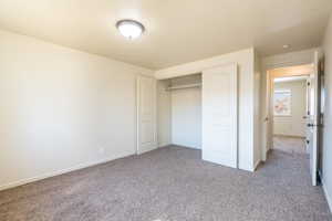 Unfurnished bedroom featuring carpet floors, a closet, and baseboards