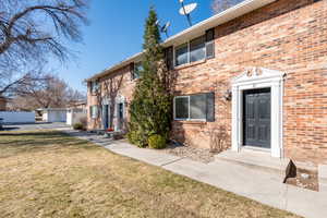 Exterior space featuring brick siding and a front lawn