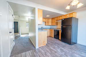 Kitchen featuring black appliances, light brown cabinets, light countertops, and a textured ceiling