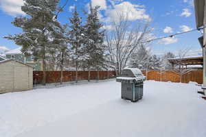 Snowy yard featuring a storage shed