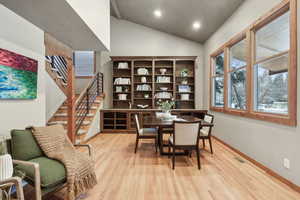 Dining space with vaulted ceiling and light hardwood / wood-style floors