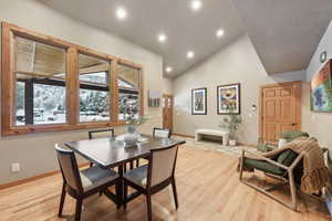 Dining area with high vaulted ceiling and light hardwood / wood-style flooring