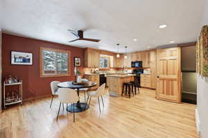 Dining space with ceiling fan, sink, light hardwood / wood-style flooring, and a textured ceiling