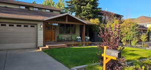 View of front of house with a garage, covered porch, and a front lawn