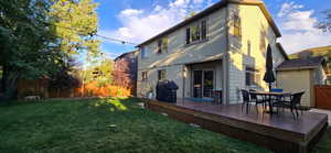 Rear view of property featuring a yard and a deck