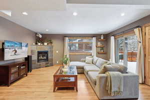 Living room featuring a wealth of natural light, a fireplace, a textured ceiling, and light wood-type flooring