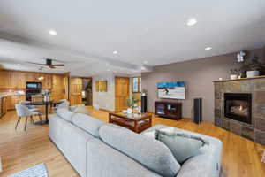 Living room featuring ceiling fan, a fireplace, and light hardwood / wood-style floors