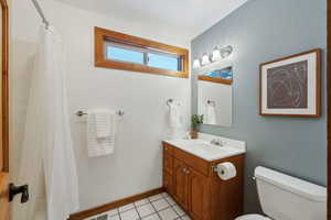 Bathroom featuring tile patterned flooring, vanity, a shower with curtain, and toilet