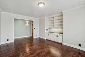 Large In-home office featuring ornamental molding, a textured ceiling, and dark hardwood / wood-style flooring