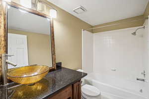 Full bathroom on basement level with tiled/stone flooring, specialty sink