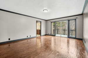 Master bedroom with siiding glass door to balcony overlooking wooded lot, hardwood floors, Crown molding and designer paint