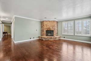 Living room featuring a fireplace, plantation shutters,  wood floors.